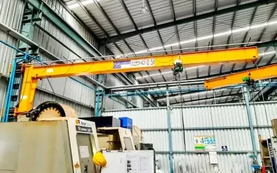 Overhead gantry crane lifting equipment inside industrial manufacturing facility